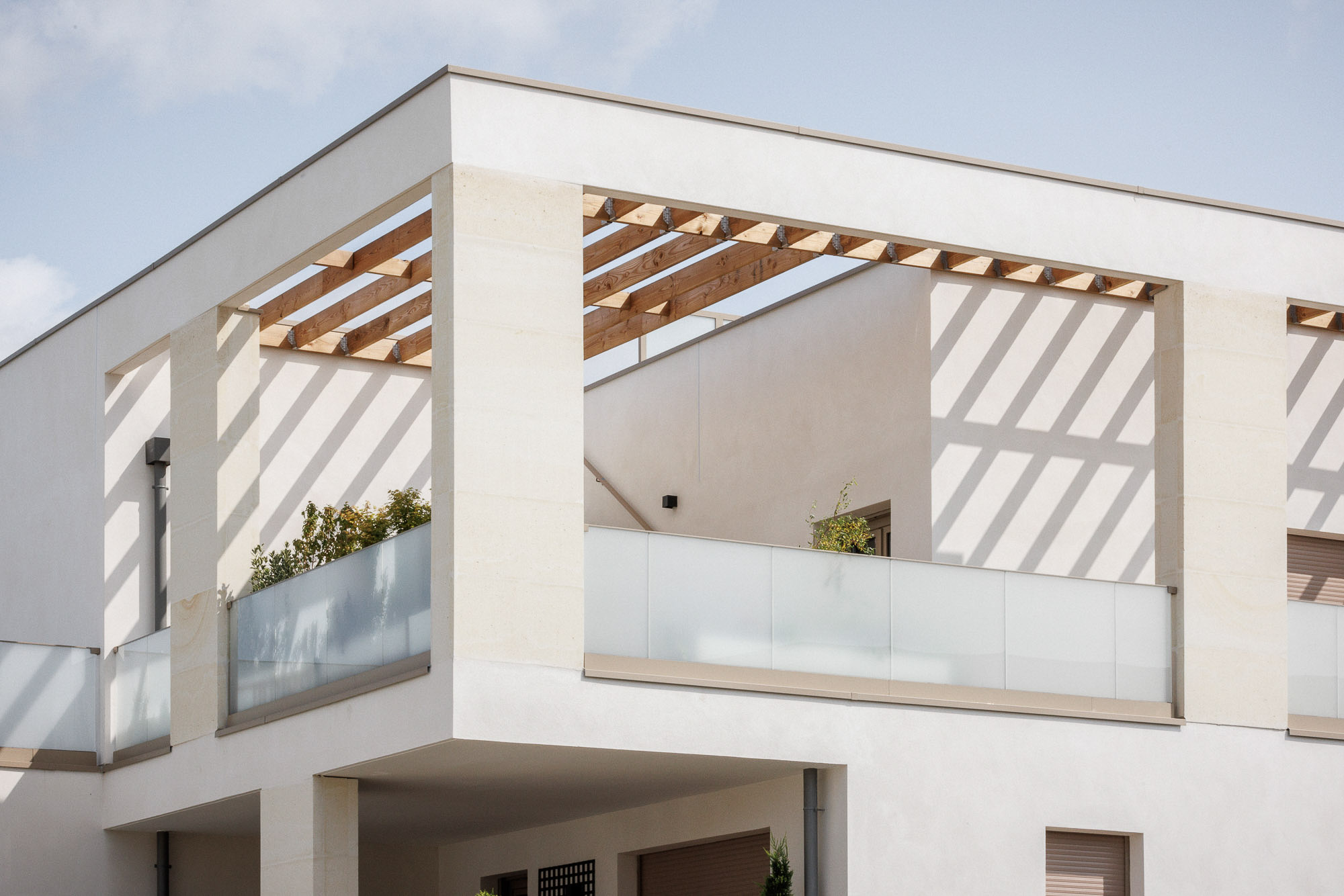 Terrasse privative d'angle élégante au dernier étage d'un immeuble de logements ZAC Jean Zay à Antony avec pergola bois, garde-corps en verre sablé.